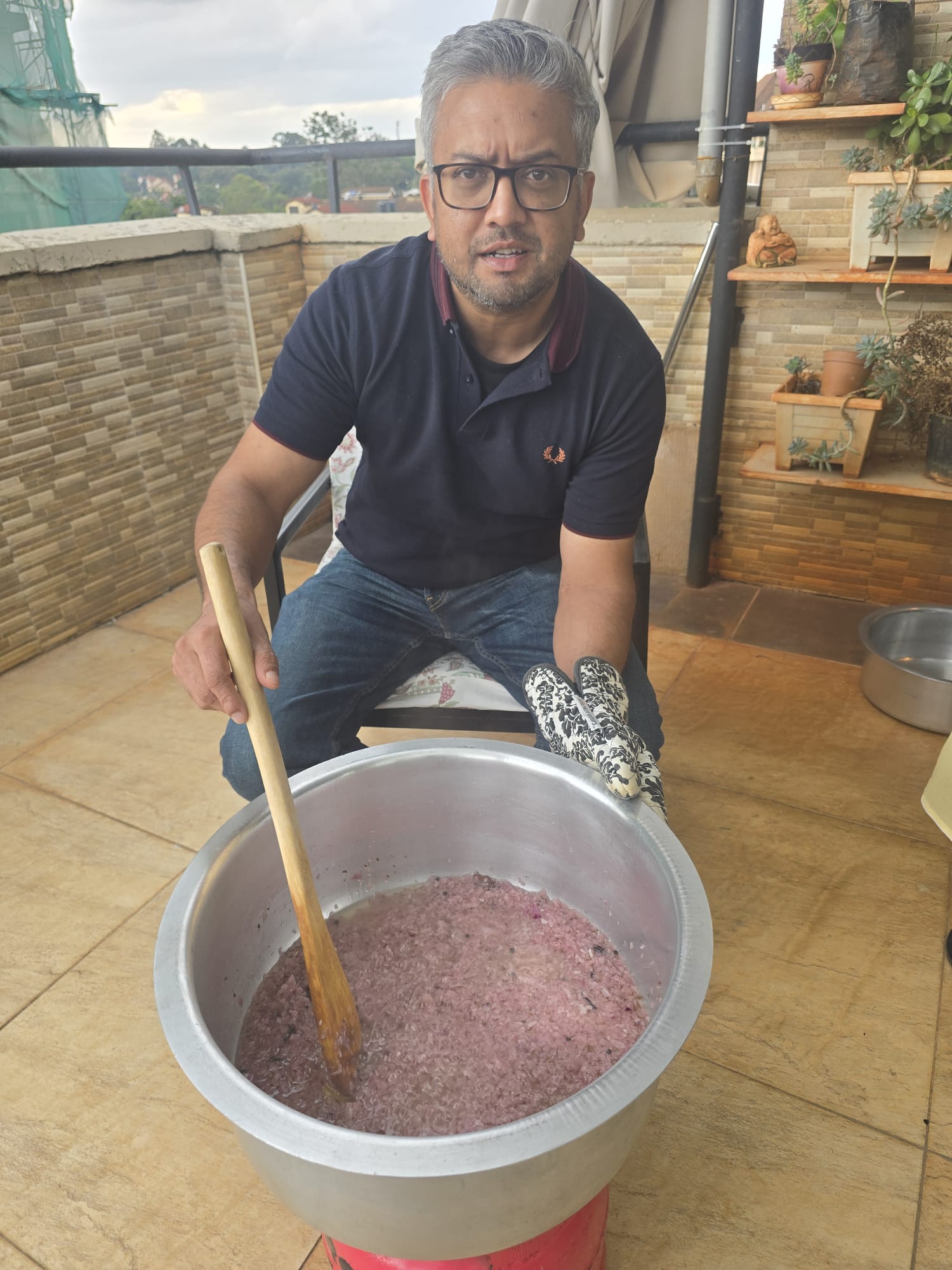 Nim cooking outdoors on a terrace, stirring a large pot